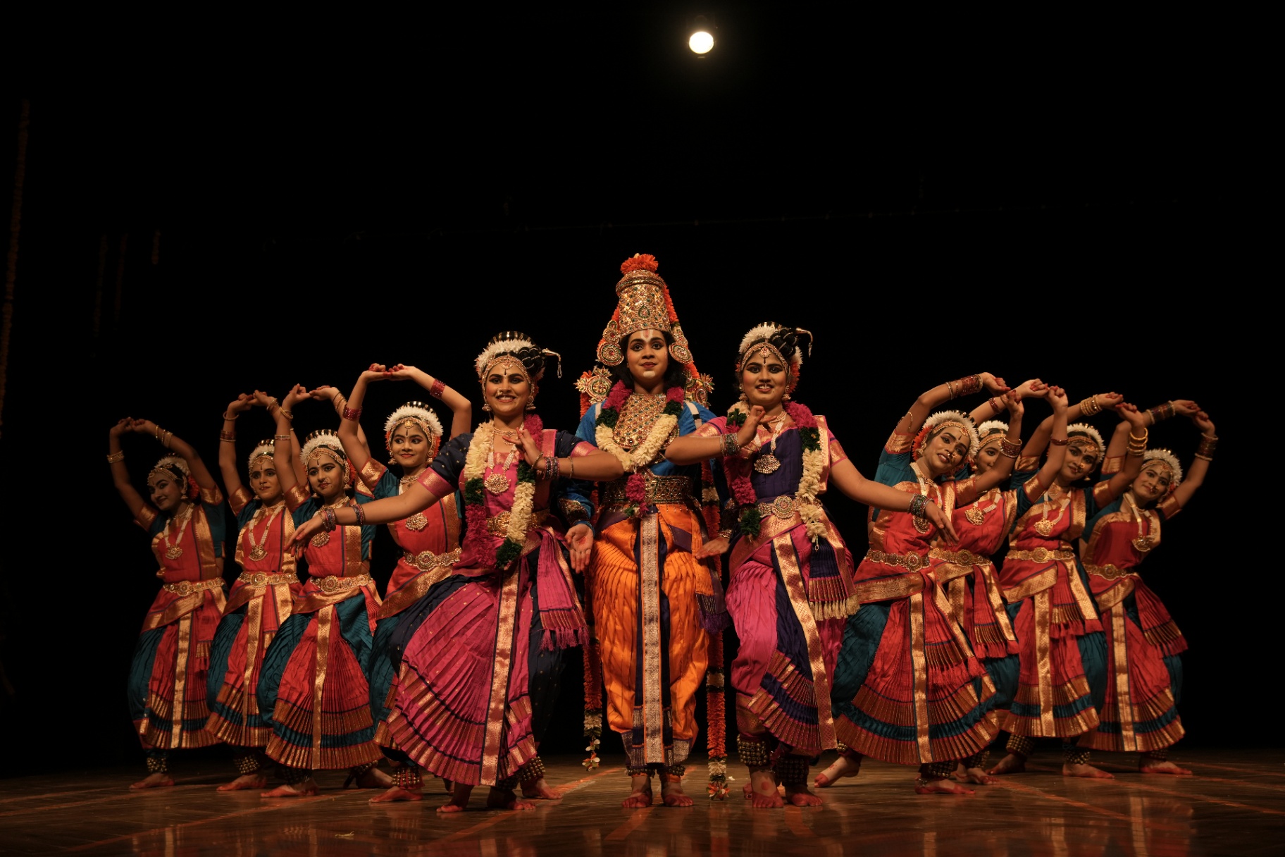 Group of Kuchipudi dancers framing the lead in a stage tableau