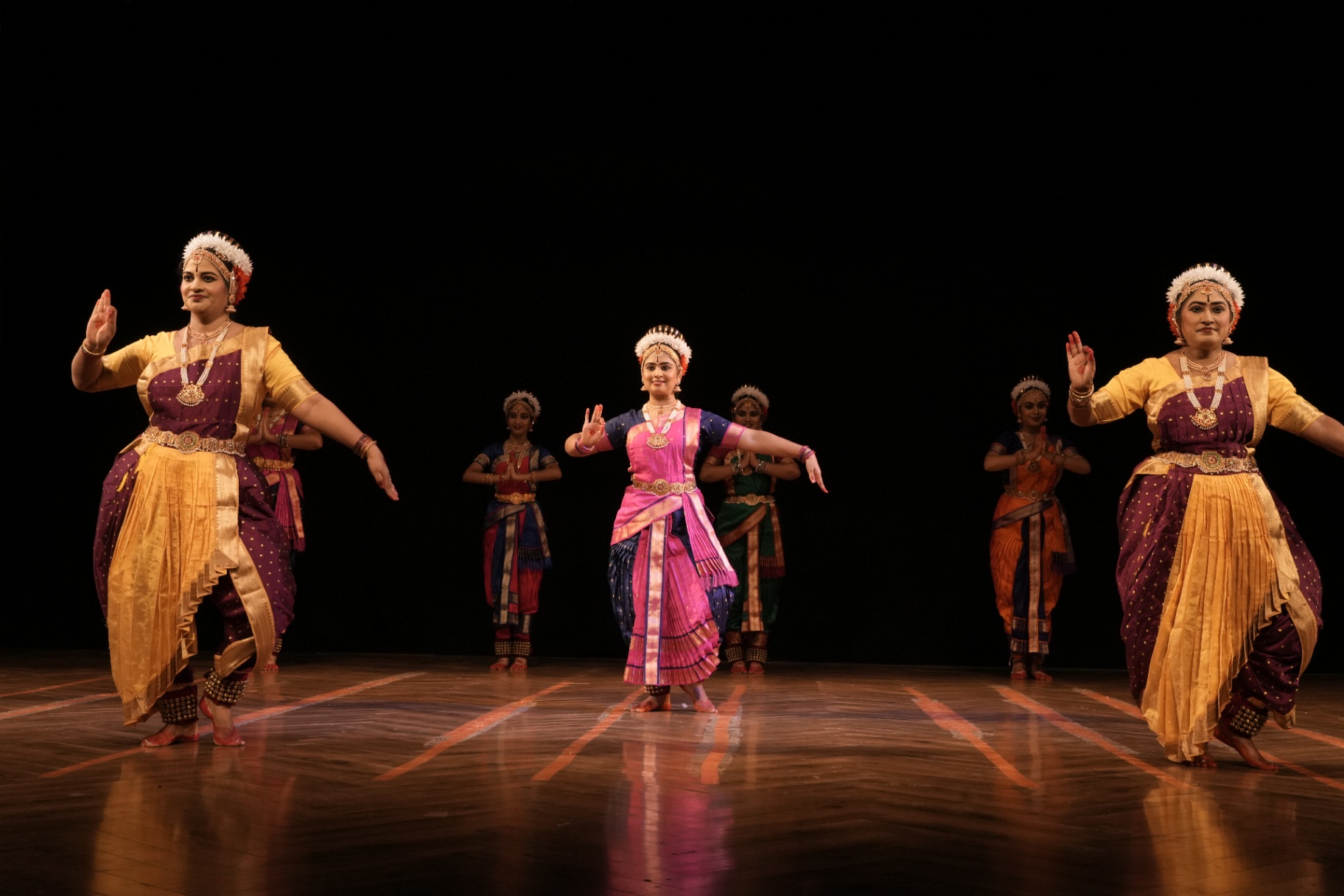 Five dancers performing in unison on a lit stage